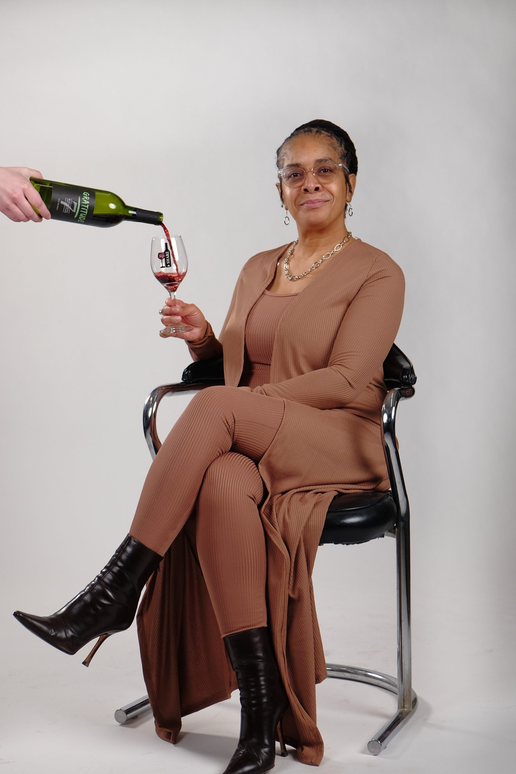 Photo of Nicole Kearney, owner of Sip and Share Wines, poses while someone pours red wine into her glass.